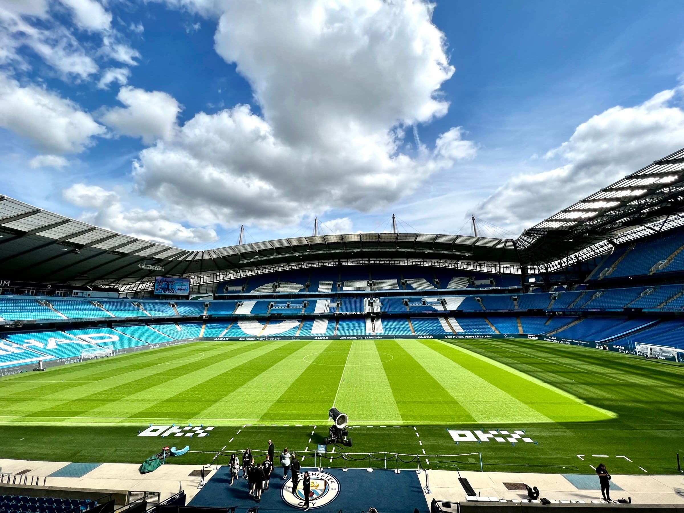 An empty football stadium and pitch under a bright sky