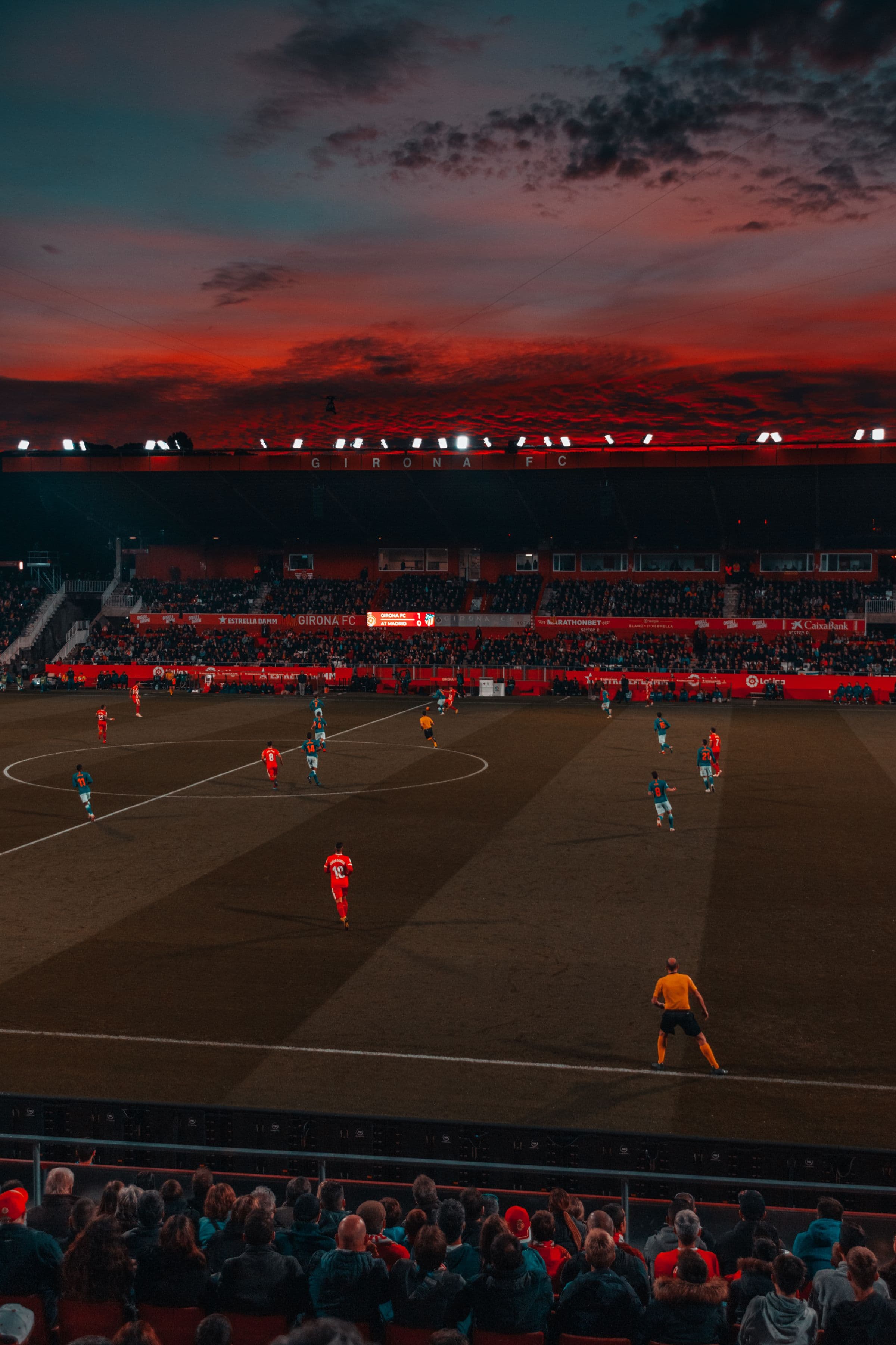 A floodlit football match at night, players on the pitch